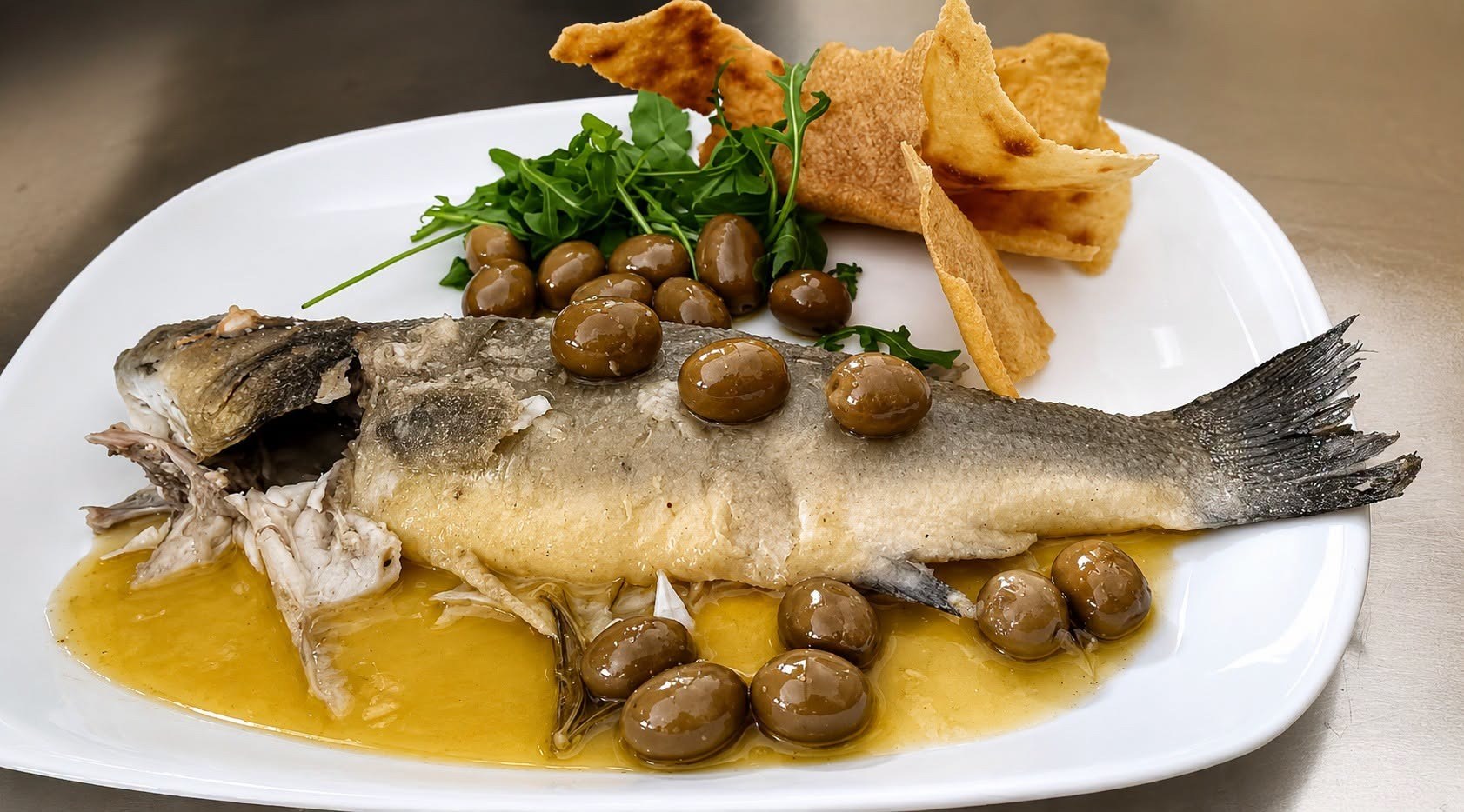 Piatto di pesce con olive e pane carasau servito a Castiadas